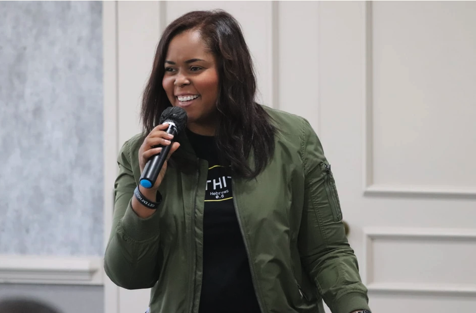 Annette speaking with a microphone, wearing a green jacket